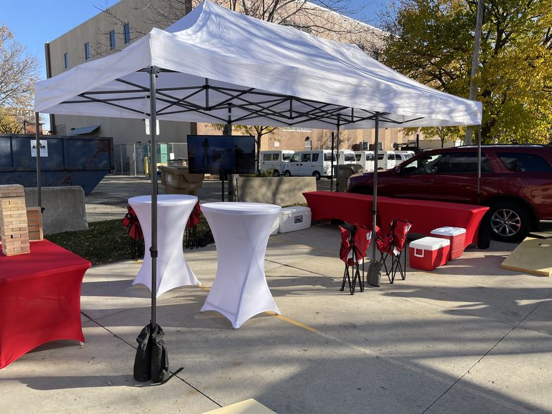 Clean 10x20 private cabana tent setup with cocktail tables and coolers at a GameDay Your Way Badgers tailgate.