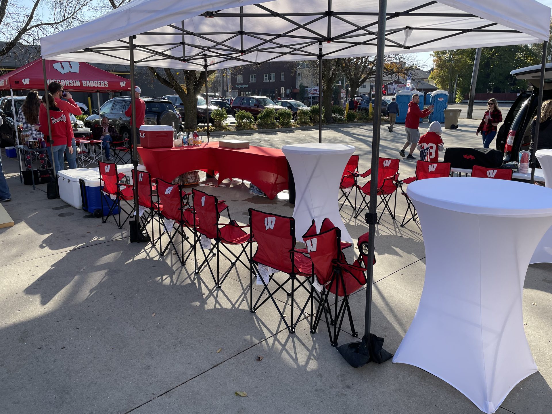 Private Badgers tailgate tent with rows of red chairs and cocktail tables set up by GameDay Your Way on Regent Street.