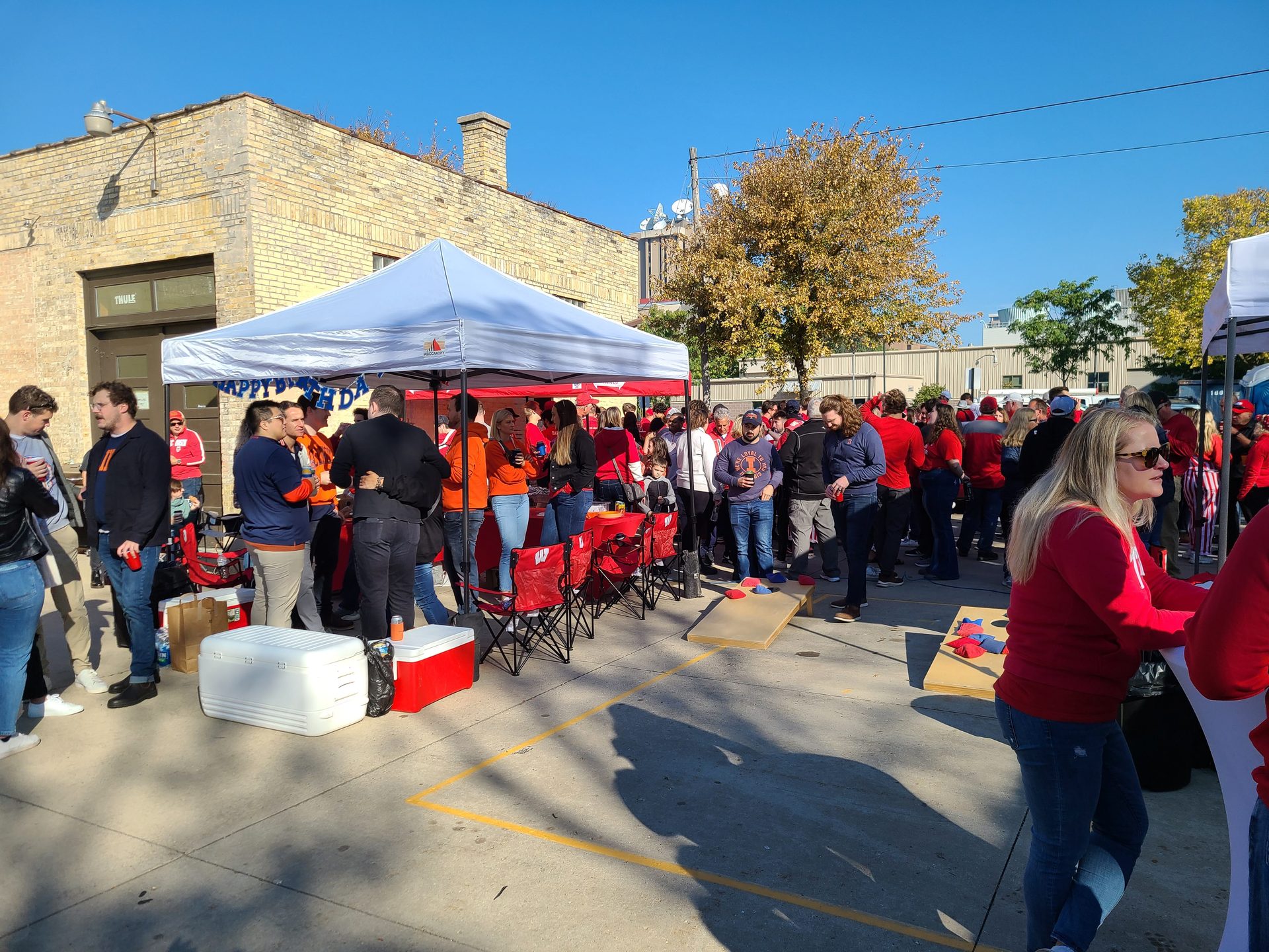 Lively Badgers game-day tailgate crowd at a GameDay Your Way setup near Camp Randall in Madison.
