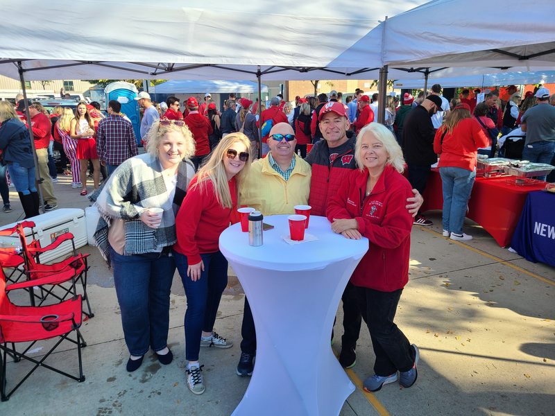 Friends gathered around a private cocktail table at a GameDay Your Way Badgers tailgate near Camp Randall in Madison, Wisconsin.